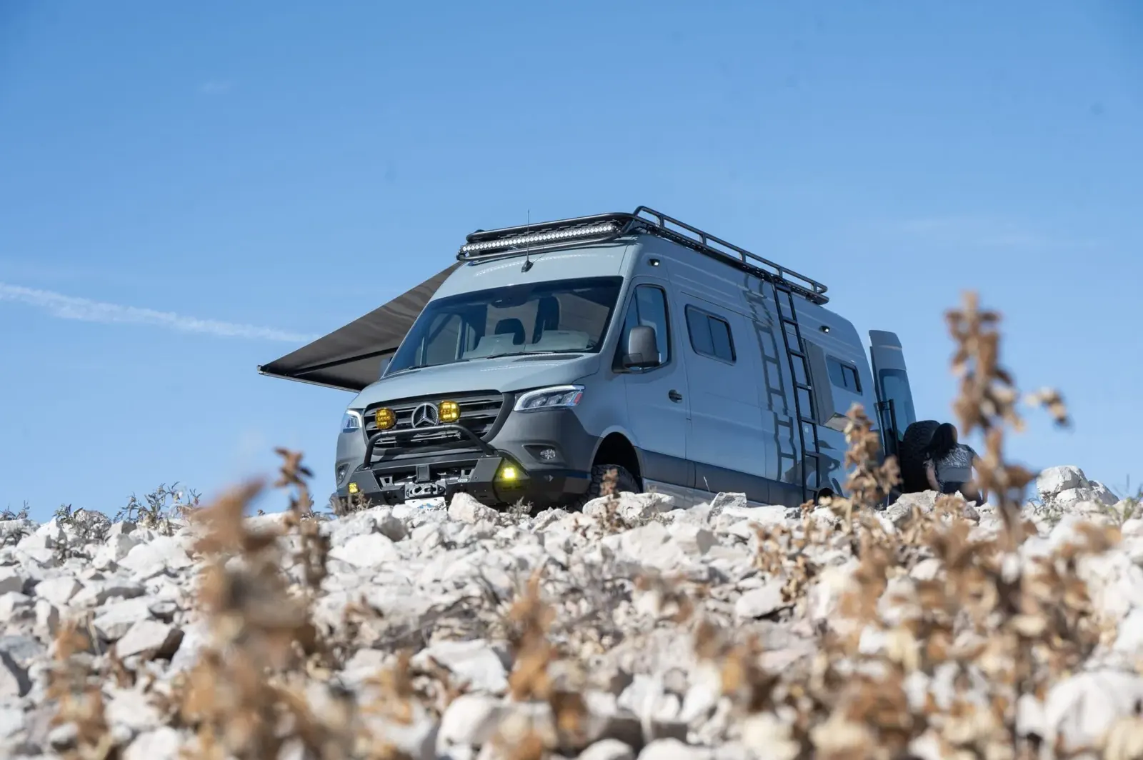 A Papago camper van with its awning out on rocky desert ground