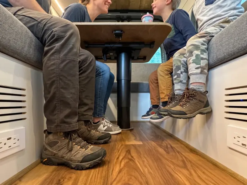 A family sitting around the dinette table of a Papago van, seen from the floor