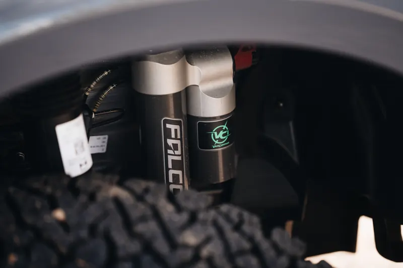 An upgraded off-road shock behind an all-terrain tire on a Papago Sprinter