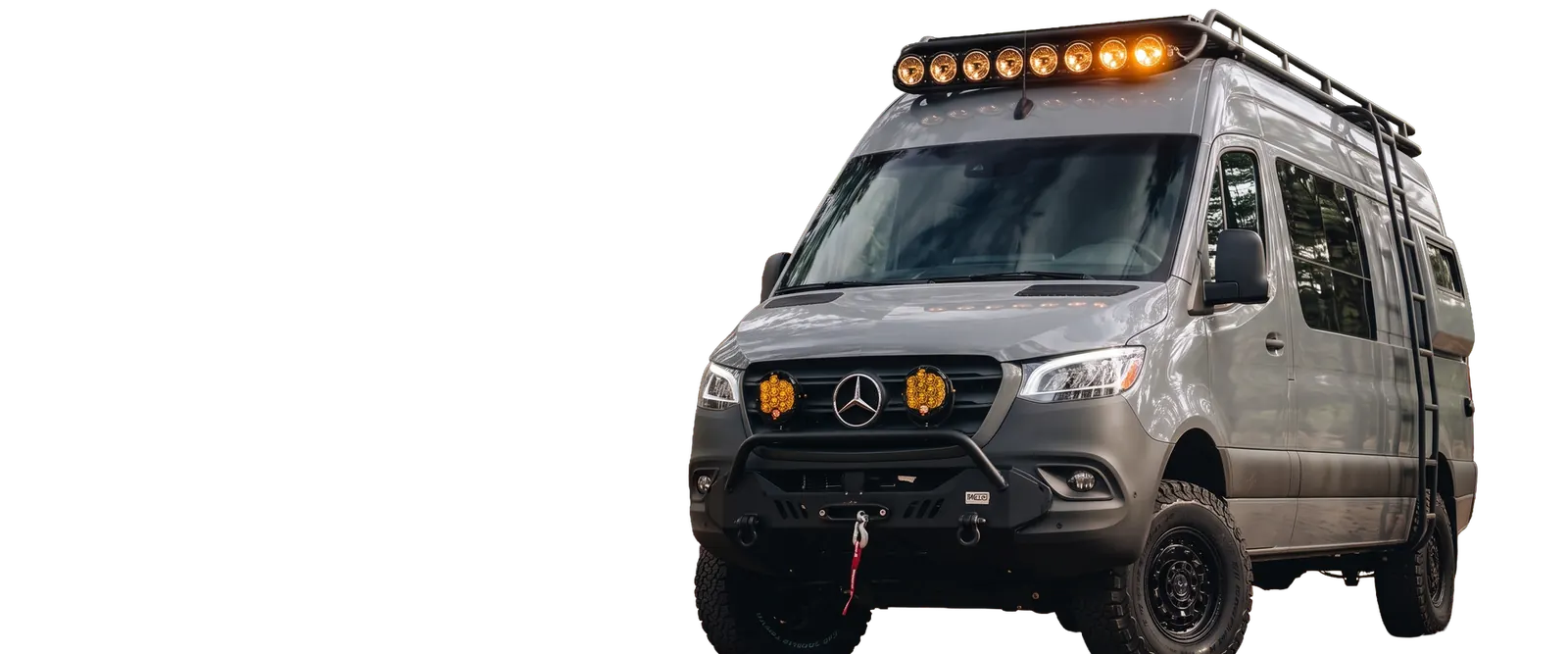 A lifted grey Papago Sprinter with a roof light bar, ladder, amber grille lights and a winch bumper
